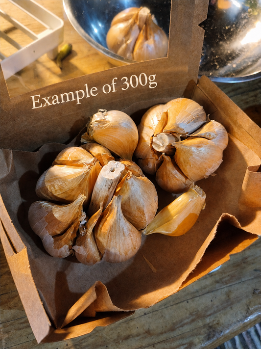 Box of garlic with a label indicating 300g on a wooden surface.
